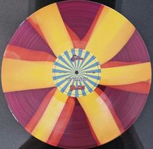 Text: "Who Believes In Angels?" Vinyl mit gelb-rotem Muster und blau-gelbem Label in der Mitte.