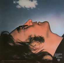 Logo: "imagine john lennon". Profil eines Mannes liegend, mit Brille, schaut in einen blauen Himmel mit Wolke.