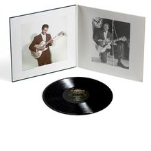 Ein offenes Album mit zwei Fotos eines Mannes mit Gitarre und eine schwarze Schallplatte mit buntem Label.