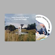 "Avalon Emerson & the Charm - Written into Changes"; Person in weiß mit Vogel auf der Hand, umgeben von Gras bei einem Teich.