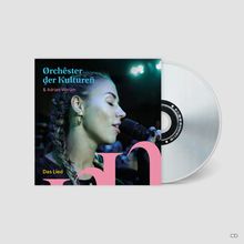 Text: „Orchster der Kulturen & Adrian Werum. Das Lied.“ Frau mit geflochtenem Haar singt ins Mikro. CD-Hülle sichtbar.