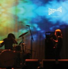 „EARTHLESS Live At Roadburn“. Eine Bühne mit zwei Musikern, einer am Schlagzeug, der andere an der Gitarre. Bunter Hintergrund.