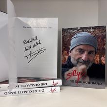 Signiertes Buch "Die geklaute Band" von Thomas Fritsching über die Band Silly. Cover zeigt älteren Mann mit Mütze.