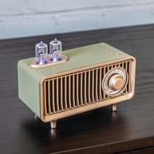Text: "Crosley." Retro-Radio mit Röhrenverstärker-Design auf einem Tisch, mit zwei leuchtenden Glastuben und Knöpfen oben.