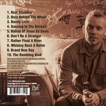 Eine Trackliste mit zehn Titeln vor einer braunen Wand. Ein Mann sitzt rechts, lehnt sich zurück und schaut in die Ferne.