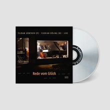 CD-Cover mit "Rede vom Glück" und Live-Aufnahme im Fenster. Abgebildet sind Musiker mit Instrumenten in einem Raum.