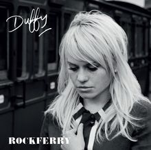 "Duffy" und "Rockferry" stehen in weißer Schrift. Eine junge Frau mit blondem Haar und ernstem Ausdruck ist in Schwarz-Weiß zu sehen.