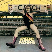 "Udo Lindenberg & Das Panik-Orchester, Sister King Kong" zeigt einen in Ringpose stehenden Mann in farbenfrohen Stiefeln.