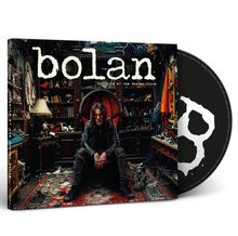 „Bolan, Gargoyles of the Garden State“. Eine Person sitzt in einem vollgestellten Raum, ein Hund daneben.