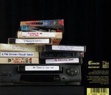 Mehrere VHS-Kassetten mit handgeschriebenen Titeln: "A Night at the Riffi Bar", "There's Waldo", "The Golden Toilet Heist".