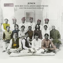 "JUNUN SHYE BEN TZUR, JONNY GREENWOOD AND THE RAJASTHAN EXPRESS" über einer Gruppe sitzender und stehender Männer in traditioneller Kleidung.