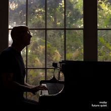 Texte: "moby future quiet". Eine Person am Klavier vor einem großen Fenster mit grünem Laub im Hintergrund.
