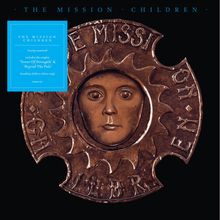 Text: "THE MISSION CHILDREN". Braunes Medaillon mit einem Gesicht in der Mitte, umgeben von einem gezackten Rand.