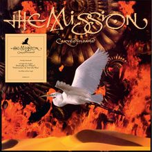 Texte: "The Mission", "Carved in Sand". Ein weißer Vogel fliegt vor Flammen und mechanischen Zahnrädern.