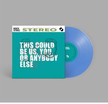 Cover mit Text "THIS COULD BE US, YOU OR ANYBODY ELSE". Blaues Vinyl daneben, Hintergrund grau.