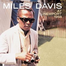 Text: "MILES DAVIS AT NEWPORT 1958." Ein Mann mit Sonnenbrille hält eine Kamera, im Hintergrund ein Zelt.