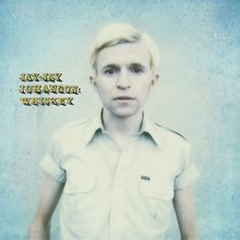 Text: "JAY-JAY JOHANSON: WHISKEY". Ein Mann mit blondem Haar in einem hellen Hemd steht vor einem blauen Hintergrund.