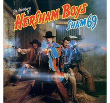 "The Adventures of Hersham Boys" und "Sham 69". Drei Männer in Westernkleidung feuern Pistolen in einer Scheune.