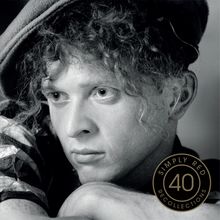 „SIMPLY RED 40 RECOLLECTIONS“; Schwarz-Weiß-Porträt einer Person mit lockigem Haar und nachdenklichem Blick.