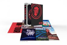 "The Rolling Stones On Tour" auf einem Buchrücken, rote Zunge auf schwarzem Hintergrund. Verschiedene Poster im Hintergrund.