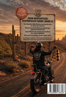 Ein Schild mit Texten zu absurden Web-Göttern und demokratischem Kitsch, im Hintergrund ein Motorradfahrer auf einer sonnigen Route.