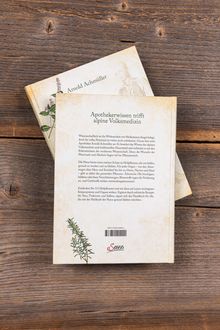 Rückseite eines Buches mit Titel "Apothekerwissen trifft alpine Volksmedizin", daneben eine Illustration von Pflanzen auf Holzhintergrund.