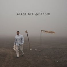 "Alles nur geliehen" über einem nebligen Weg mit einem Mann und einem Wegweiser.