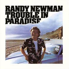 "RANDY NEWMAN TROUBLE IN PARADISE" in großen schwarzen Buchstaben über einem Mann an einem Strand mit Auto.