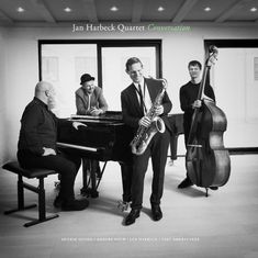 „Jan Harbeck Quartet: Conversation“. Vier Männer mit Saxophon, Piano und Bass in einem modernen Raum.
