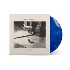 "Bruce Hornsby", "Indigo Park". Illustration: Eine Person geht allein in einer schattigen Szene, blaue Vinyl-Schallplatte.