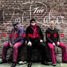 "Vienna Red" in roten Buchstaben. Drei Männer in roter Kleidung vor einer Backsteinwand mit weißer Schrift.