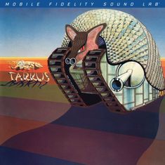 Der Text lautet "Tarkus". Ein gepanzertes Tier mit Ketten und einer Kanone, vor einem farbigen Streifen-Hintergrund.