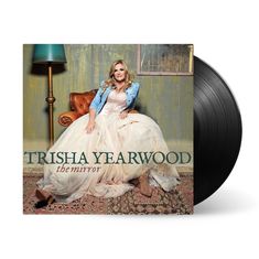 „TRISHA YEARWOOD the mirror“. Eine Frau in einem eleganten Kleid sitzt auf einem Sessel, neben einer Stehlampe.