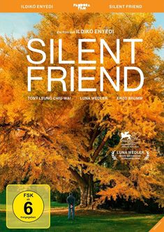 "Silent Friend" steht in großen Buchstaben. Ein Mann steht vor einem großen Baum mit goldenen Blättern.