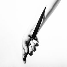 Keine Texte zu erkennen. Eine Hand hält ein langes, schmales Messer mit der Klinge nach unten. Schwarz und weiß.