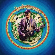 „Jan Akkerman My Focus Live Under the Rainbow.“ Illustration eines Gitarristen vor buntem Hintergrund aus Häusern und Palmen.