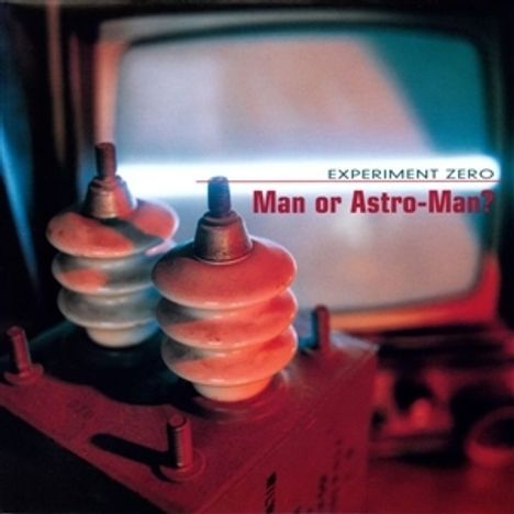 "EXPERIMENT ZERO" und "Man or Astro-Man?" in weiß und rot. Zwei elektrische Isolatoren im Vordergrund, verschwommener Bildschirm.