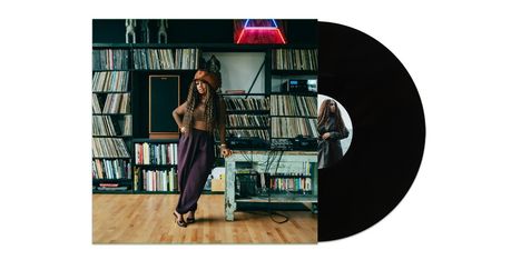 Eine Frau lehnt an einem Tisch, umgeben von Regalen voller Schallplatten und Büchern. Vinyl-Schallplatte rechts.