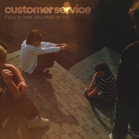 Text: "customer service" und "if you're here, you must be fine." Vier Menschen sitzen entspannt auf einem Hausdach.