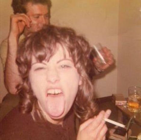 Es gibt keinen Text zu beachten. Zwei Personen sind zu sehen, eine zeigt eine lustige Grimasse und hält eine Zigarette, die andere trinkt.