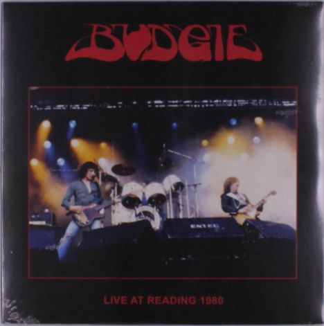 Text: "BUDGIE" und "LIVE AT READING 1980". Konzertszene mit Musikern auf der Bühne, bunte Scheinwerfer im Hintergrund.