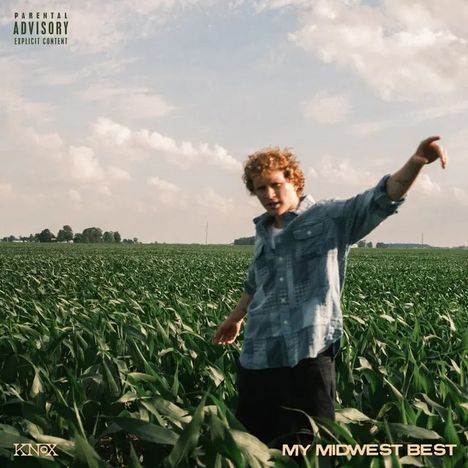 "MY MIDWEST BEST" unten rechts. Ein junger Mann in Jeanshemd steht in einem weitläufigen Maisfeld unter bewölktem Himmel.