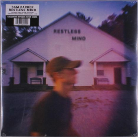 "RESTLESS MIND" auf einem großen Gebäude. Unscharfe Person mit Baseballkappe im Vordergrund.