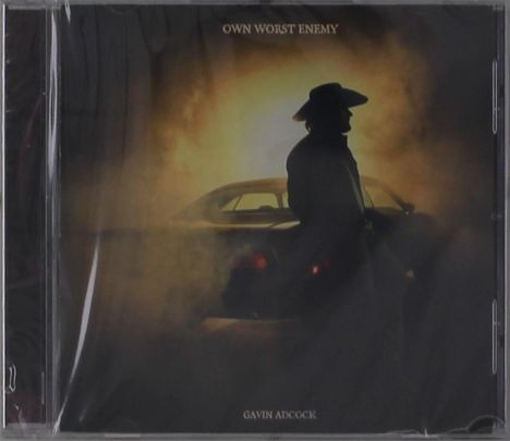 Text: "OWN WORST ENEMY" und "GAVIN ADCOCK". Silhouette einer Person mit Hut lehnt an einem Auto im Nebel.