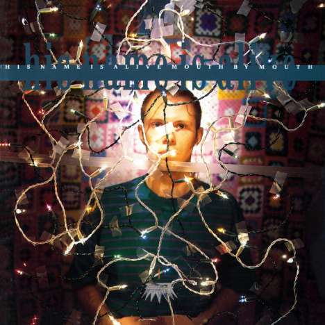 Text: "HIS NAME IS ALIVE MOUTH BY MOUTH". Eine Person mit Lichterketten umgeben, vor gemustertem Hintergrund.