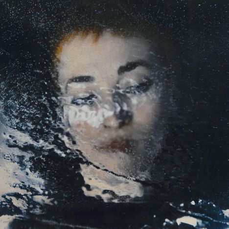 Du hast keine Texte im Bild. Gesicht einer Person unter halbtransparentem Wasser, Augen geschlossen, entspannte Stimmung.