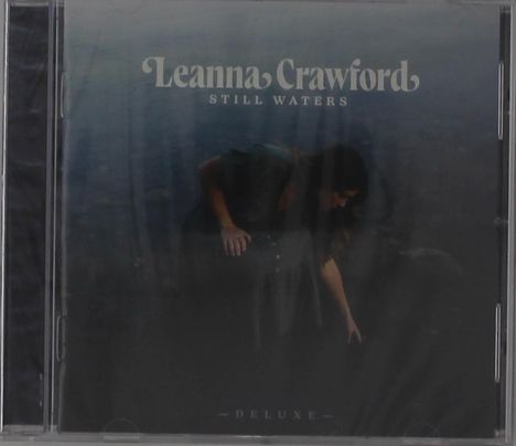 "Leanna Crawford Still Waters Deluxe" in weißer Schrift. Frau beugt sich nach unten, dunkler Hintergrund.