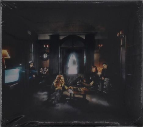 Ein dunkler Raum mit vier Personen auf einem Sofa, ein Fernseher links flackert, im Hintergrund eine helle Türöffnung.