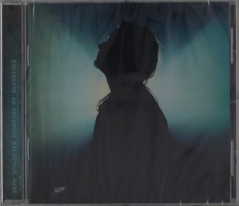 Text: "Seph Schlueter Counting My Blessings". Silhouette einer Person schaut nach oben, vor einem diffusen, blauen Hintergrund.