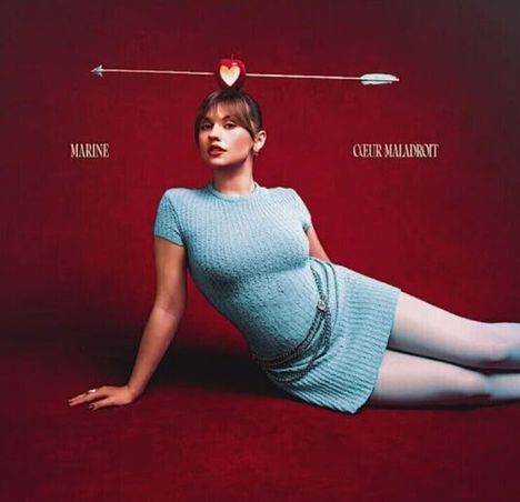 Texte: "MARINE", "COEUR MALADROIT". Frau in blauem Kleid liegt auf rotem Hintergrund. Herz-Pfeil über ihrem Kopf.